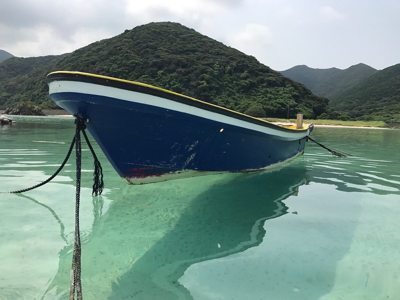 透き通った海に浮かんだ小舟が、まるで宙に浮いているように見える写真。