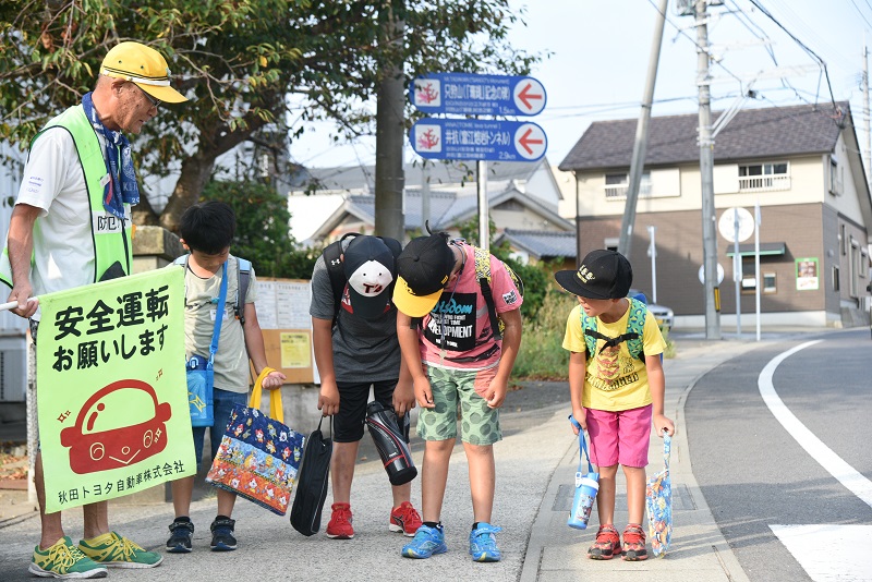 交通安全指導員へおじぎする4人の子どもたち