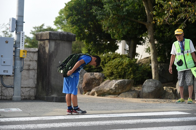 交通安全指導員へおじぎをする青い服を着た男の子