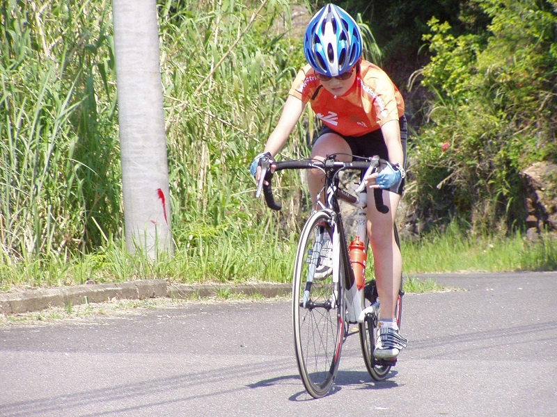 青いヘルメットをかぶり、競技用自転車に跨る出口さんを写した写真。